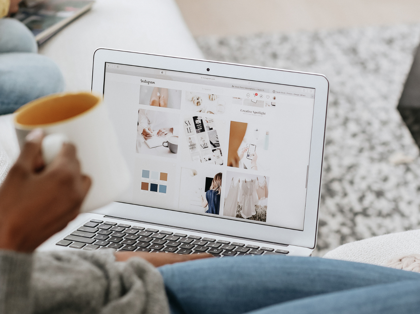 Entrepreneur sitting on the couch with a cup of coffee, using her laptop to research and get inspiration for what social media platforms are right for her own business.